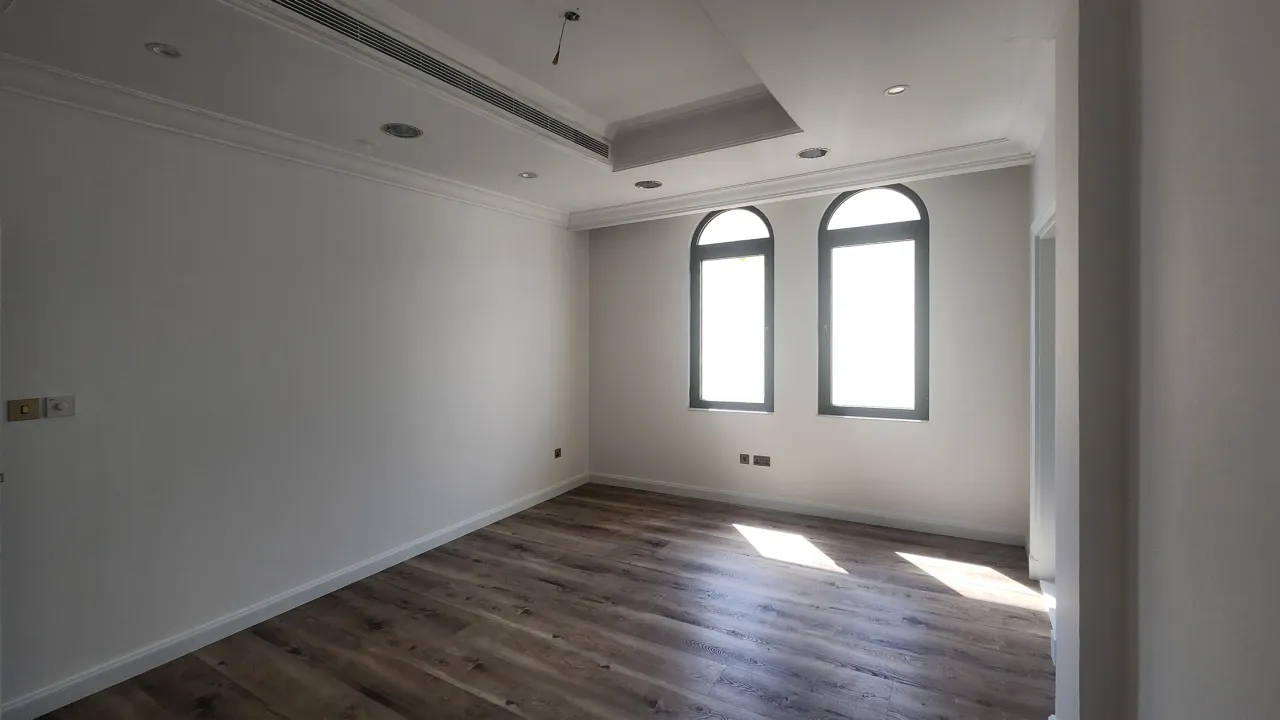 Guest bedroom before remodeling with arched windows and dark wood flooring in Palm Jumeirah villa