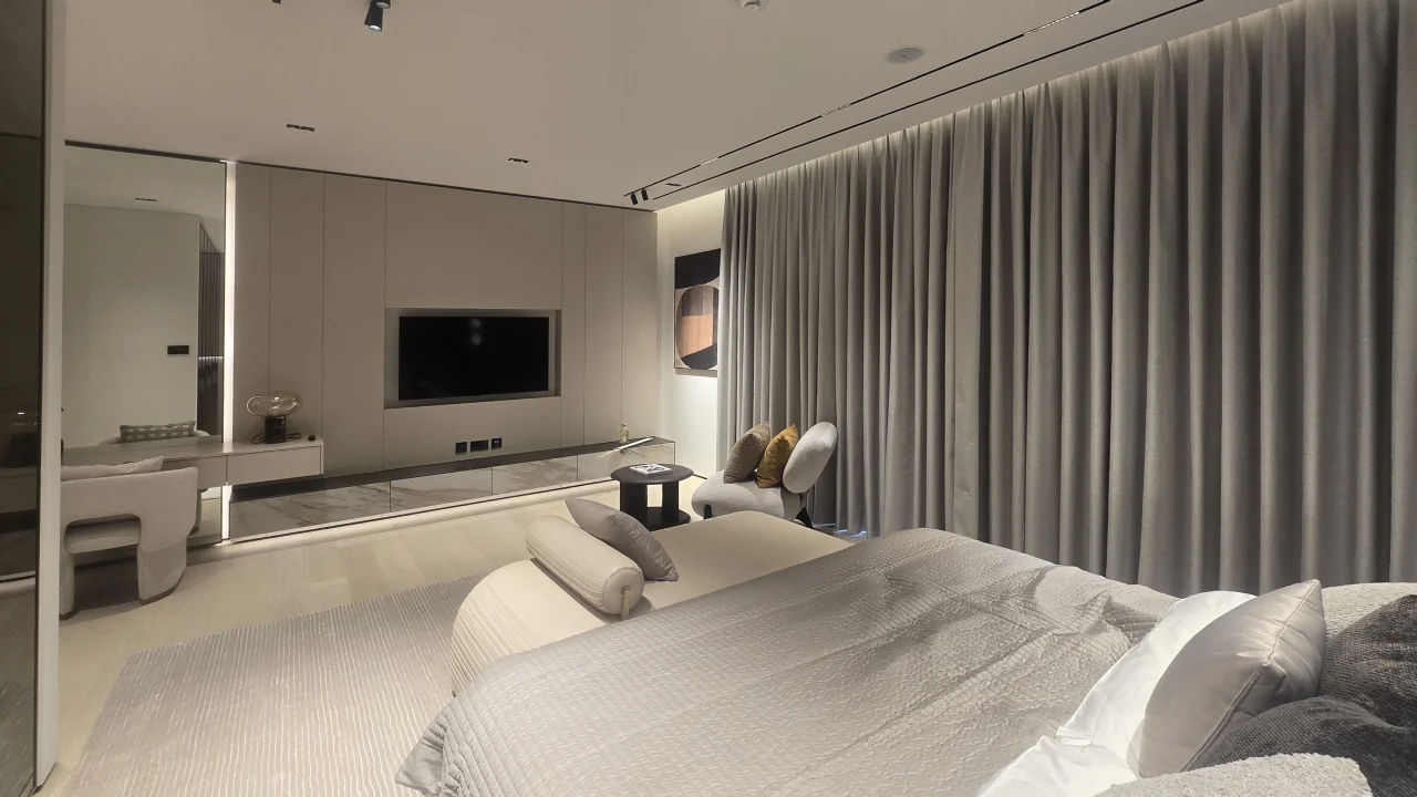 Palm Jumeirah guest bedroom after renovation with recessed television, low joinery, dressing table and full-height curtains