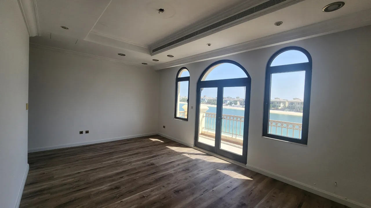 Palm Jumeirah bedroom before remodeling with plain walls, dark flooring and Mediterranean arched openings