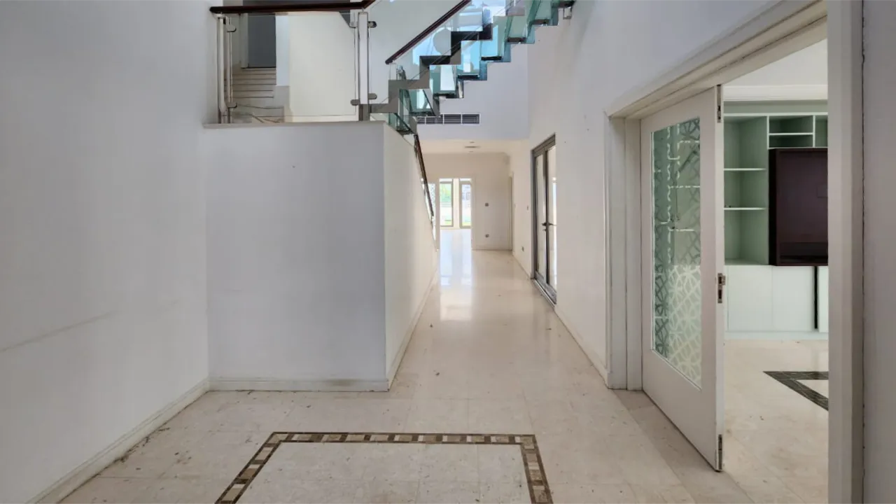 Original Palm Jumeirah villa entrance hall with glass balustrade staircase, timber handrails and decorative marble floor border